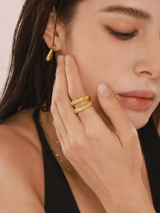 Detail of gold-plated textured hammered rings and layered necklaces on a model