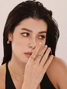 Detail of model wearing a gold wavy enamel ring and layered necklace with a pearl