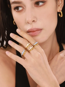 Macro view of gold mountain wave rings with light blue enamel and zircon hoop earrings