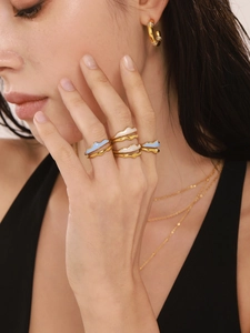 Detail of gold-plated wavy rings with blue and white enamel glaze on a female model