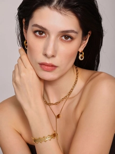 Details eines eleganten Goldschmuck-Sets mit Strassohrringen und Schichtketten am Modell