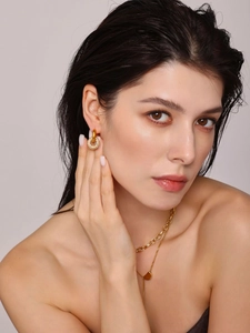 Details goldene Doppel-Creolen mit Zirkonia und mehrlagige Herz-Halskette an Model