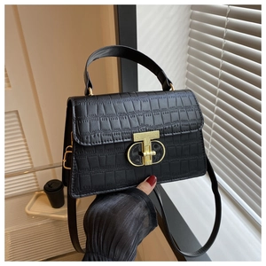 Detail of black crocodile texture handbag with gold metal clasp and top handle