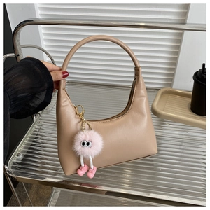 Close-up of minimalist beige PU leather shoulder bag with a pink plush charm detail