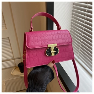 Detail of rose pink crocodile pattern handbag with golden metal twist lock and top handle