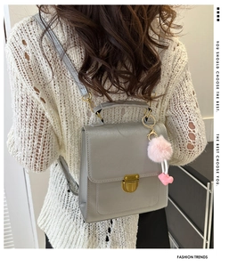 Gray leather backpack detail with gold metal lock and pink faux fur heart keychain