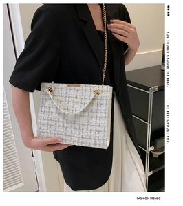 Detail of tweed crossbody bag featuring white and gold woven texture with metal chain
