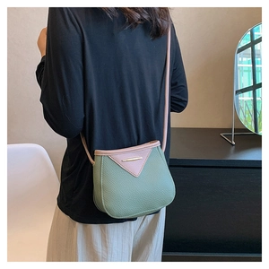 Litchi texture green and pink leather bucket bag shown as crossbody on person