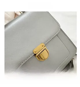 Close-up of grey textured leather backpack featuring a vintage gold metal flip-lock buckle