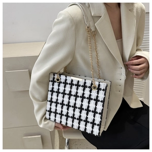 Close-up of black and white plaid tweed tote bag with chain strap and gold clasp