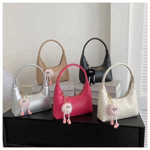 Five colorful hobo bags with eye-shaped plush charms displayed on books for detail