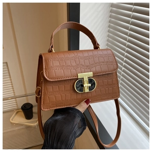 Close-up of brown crocodile texture handbag featuring a unique gold metal clasp and top handle