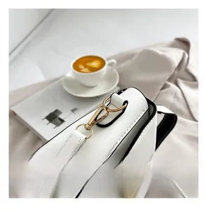Close-up of premium gold metal hardware and lock on white retro crossbody bag