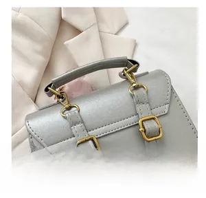 Macro shot of grey leather bag with golden clasp and pink pompom accessory