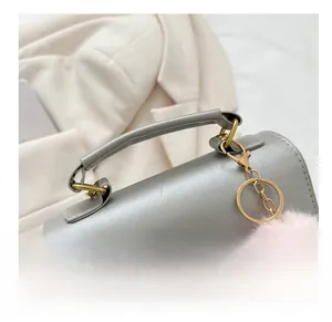Detail of silver grey handbag handle with gold buckles and pink fuzzy charm