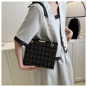 Detailed view of elegant black tweed shoulder bag with gold chain strap on model