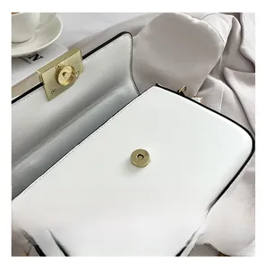 Close-up of white leather handbag featuring premium light gold magnetic hardware detail