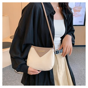 Detail of a chic cream and brown crossbody bag showing the leather texture and gold metal trim