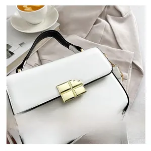 Detail of white leather flap bag with gold square lock and contrast handle in a city set