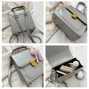 Detail view of silver backpack showing golden metal lock and protective bottom rivets