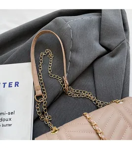 Detail of beige quilted bag with V-shaped stitching and golden metal chain strap