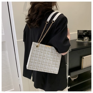 Detailed texture of tweed shoulder bag with gold chain strap on black blazer