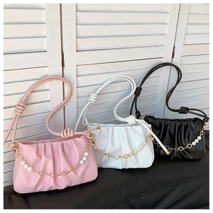 Detail view of colorful pleated shoulder bags with pearl and flower chain accents