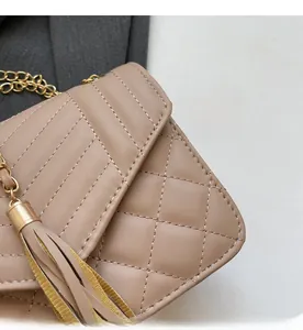 Detail of beige quilted leather bag with elegant gold chain strap and stylish tassel