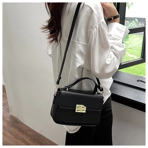 Detail of elegant black leather crossbody bag with textured gold rectangular twist lock
