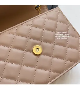 Close-up of golden magnetic buckle and chain on beige quilted crossbody bag