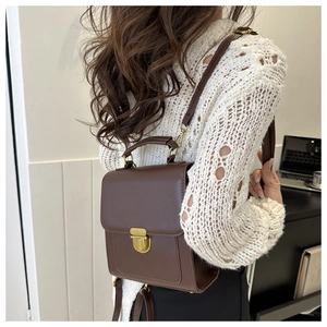 Macro detail of a vintage brown leather backpack with gold metal clasp on the top
