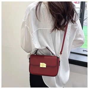 Detail of burgundy leather crossbody bag featuring a premium gold square mechanical clasp