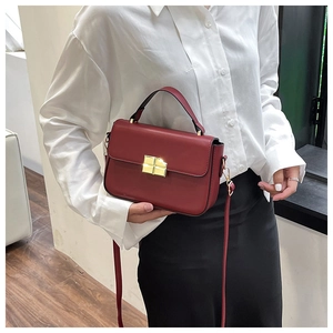 Detail of a vintage dark red leather square bag with a golden square twist-lock closure