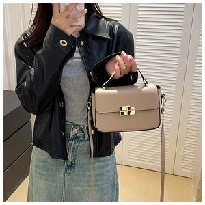 Detail shot of beige crossbody bag featuring gold metal lock and adjustable shoulder strap