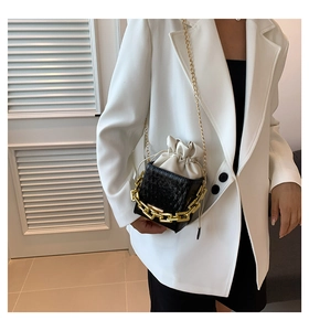 Close-up of black crocodile pattern bucket bag with gold chain strap and drawstring inner