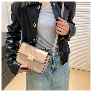 Model showing a beige crossbody bag with gold lock and black leather jacket styling