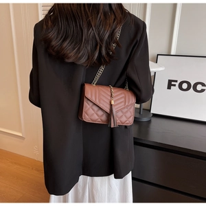 Brown quilted PU leather crossbody bag with gold chain and tassel on a model back view