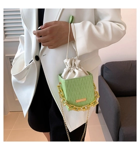 Close-up of green checkered bucket bag with gold chain and drawstring inner pouch
