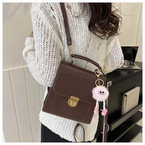Detail of vintage brown shoulder bag with gold clasp and pink plush charm accessory
