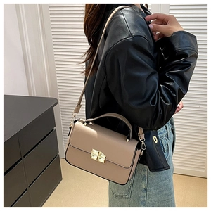 Detail view of beige crossbody bag with golden cross turn-lock and textured leather finish