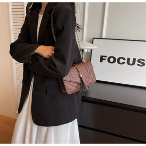 Close-up of brown quilted crossbody bag with gold chain strap and stylish tassel detail