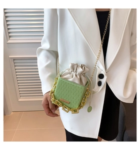 Detail of light green bucket bag with wavy texture and chunky gold chain links