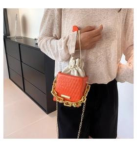 Close-up of orange plaid bucket bag featuring chunky gold chain and drawstring inner pouch