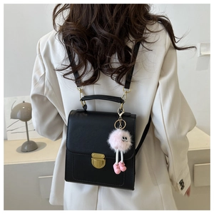 Modella indossa zaino nero vintage in pelle con pompon rosa e chiusura dorata