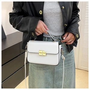 Modern white square handbag with golden buckle worn by a model in a black leather jacket