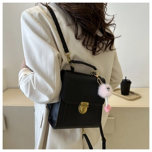 Detail of black retro small square bag featuring vintage gold buckle and pink plush charm