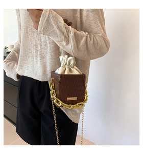 Brown textured bucket bag with white drawstring inner bag and golden chain strap detail