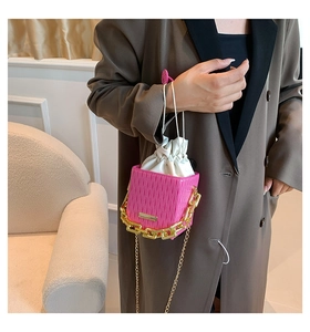 Detail of bright pink mini bucket bag with gold chain strap and drawstring inner bag