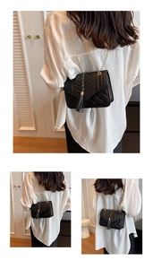 Detail of black quilted crossbody bag with gold chain strap and leather tassel accent