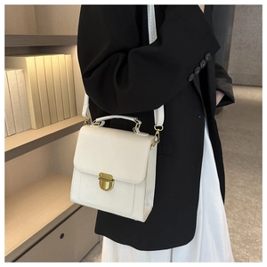 White minimalist crossbody bag with gold hardware shown being worn by a model